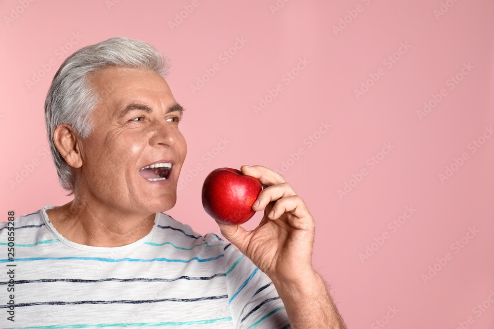 Mature man with healthy teeth and apple on color background. Space for text Mature man with healthy teeth and apple on color background. Space for text