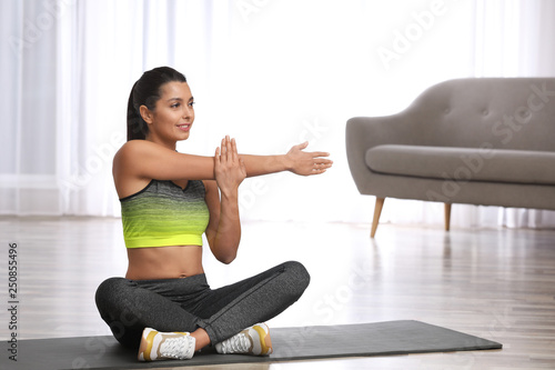 Young woman in fitness clothes doing exercise at home