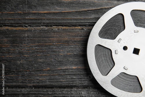 Movie reel on wooden background, top view with space for text. Cinema production