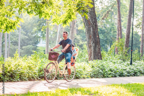 people, leisure and lifestyle concept - father with kid on bicycles.