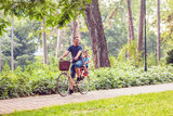 people, leisure and lifestyle concept - father and son riding a bicycle together outdoors in a city park.