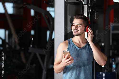 Young man with headphones listening to music on mobile device at gym © New Africa