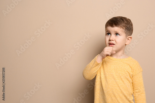 Cute boy suffering from cough on color background. Space for text