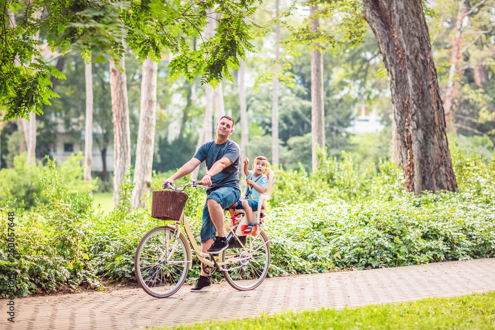 Smiling father with boy on bicycles having fun in park. .