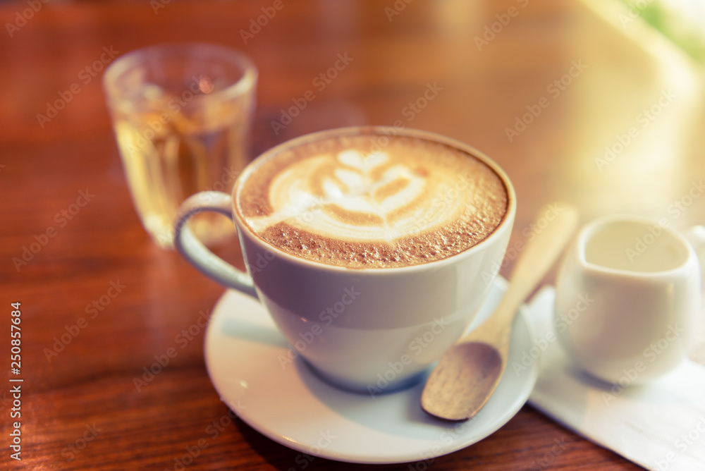 Obraz premium Coffee Espresso. Cup Of Coffee with latte art foam on wood table near window with light shade.