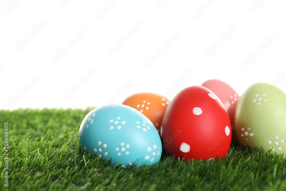 Colorful painted Easter eggs on green grass against white background