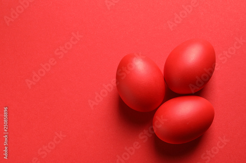 Flat lay composition of red dyed Easter eggs on color, space for text