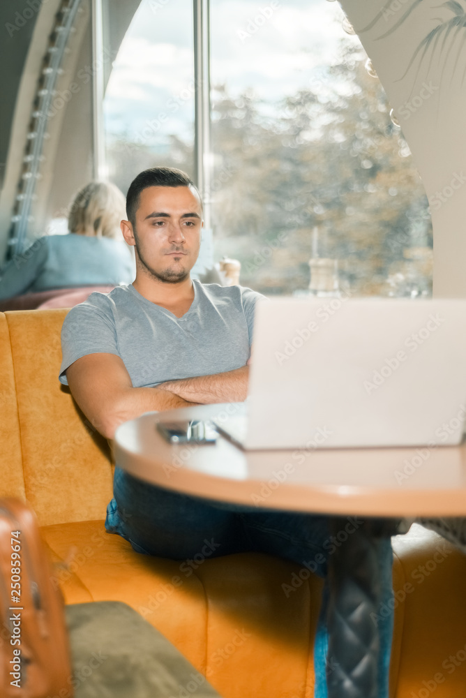 young guy works in a cafe for a laptop. the man pondered and focused young guy works in a cafe for a laptop. the man pondered and focused