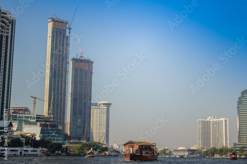 River view of Chao Phraya river with boat tours, bridge, hi-rise buildings and tourist attractions. The tourist boat takes visitors for sightseeing tour in Bangkok along the Chao Phraya River. photo