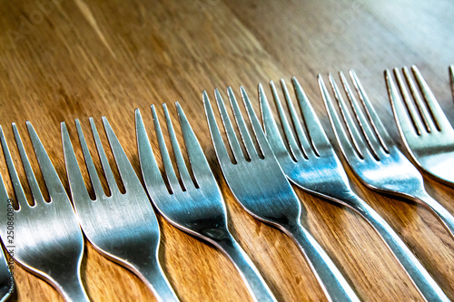 Various Forks in a row up close on a wooden table