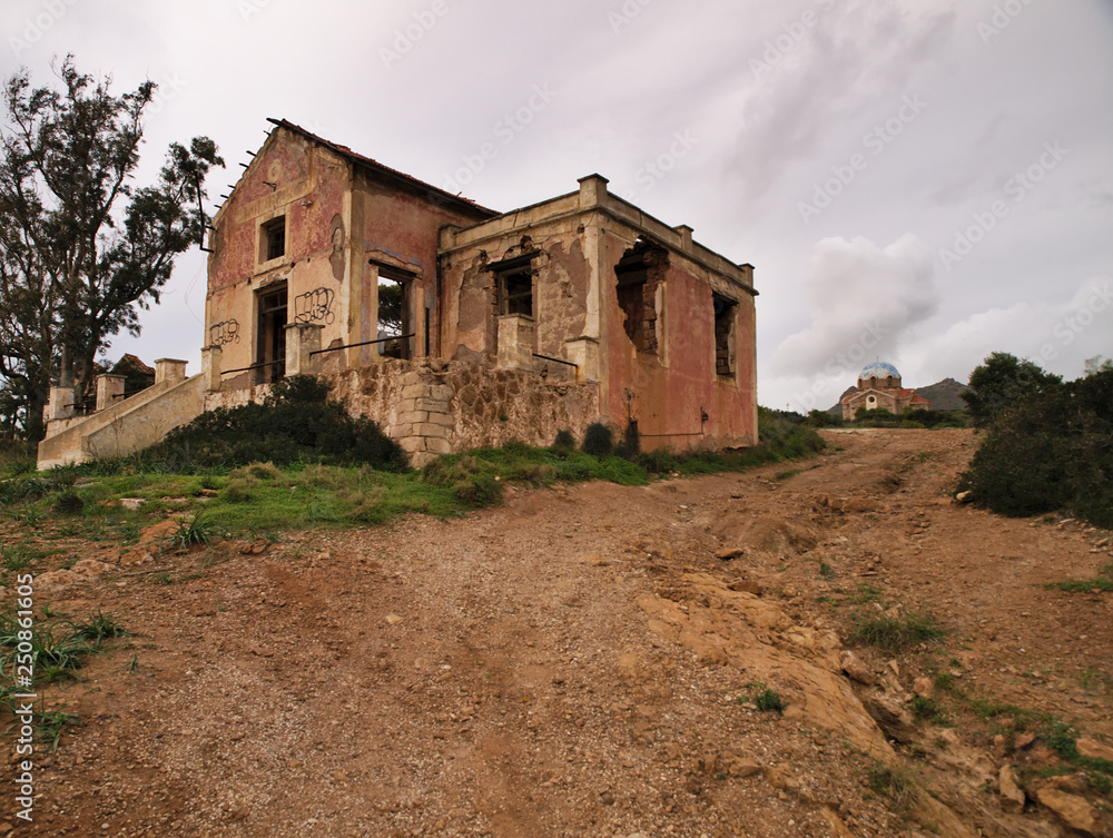 Old ruined building and church on a cliff, under sky with clouds, in Attica Greece,