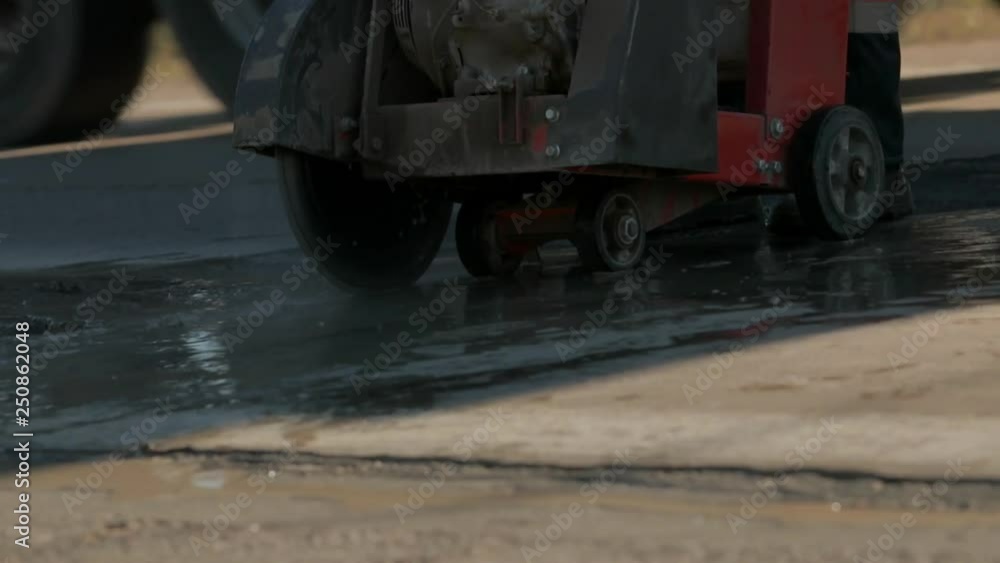 Close up cutting concrete floor with diamond saw blade machine. Cutting asphalt for repair by grinder. Road works concept. Teamwork. Group of workers on a road construction. Team of people at work. Close up cutting concrete floor with diamond saw blade machine. Cutting asphalt for repair by grinder. Road works concept. Teamwork. Group of workers on a road construction. Team of people at work.