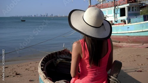 Beautiful girl with long hair sitting on an old tramp boat in the fields  photo