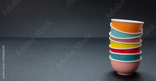 Colorful clean ceramic bowls stacked on black color background, copy space