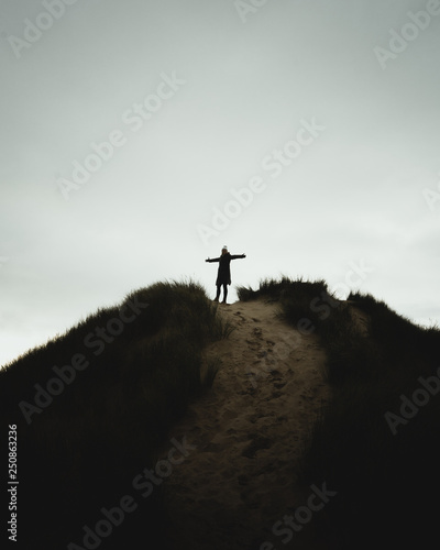 silhouette of woman on top of sand dune