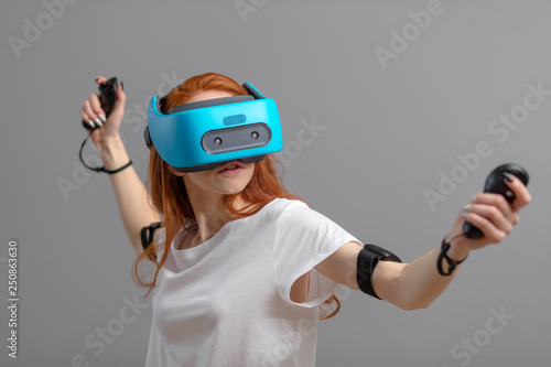 Young woman having fun with new trends innovation technology - Gaming concept - Isolated studio shot of redhead woman with blue mobile vr headset Future technology concept.