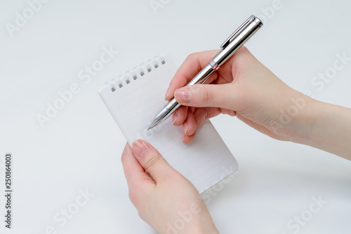 メモ帳にペンで何か書いているところ