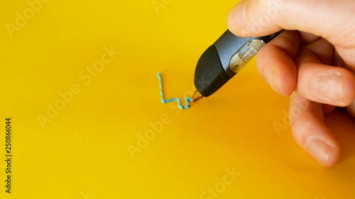 hand of a man draws with a 3d printer pen the bitcoin symbol on yellow background, footage ideal for topics such as innovation, technology and houses photo