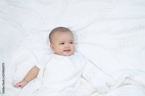 Smiling Asian newborn baby wear white shirt laying down on white background