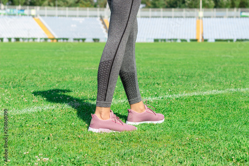 Woman with pink sneakers standing on football field with the white line. ready for running on the stadium