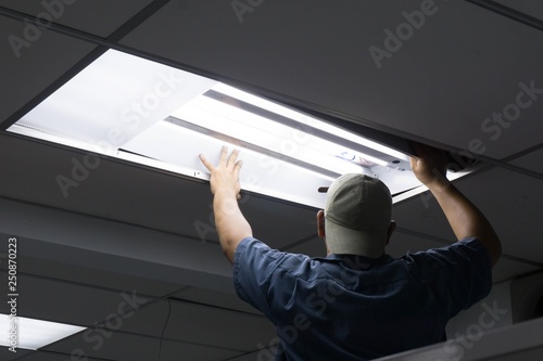 The man checking or changing Fluorescent light tube in the building. photo