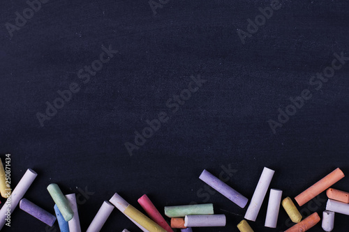 Multicolored crayons lie on a black chalkboard, copy space. The concept of school, education and childhood. photo