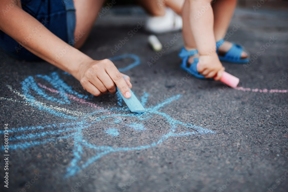 Obraz premium Close up of little girl drawing with chalks on the sidewalk