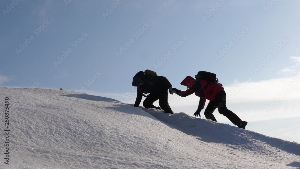 climbers hand in hand climb to top of a snowy mountain. team of travelers in winter go to their goal of overcoming difficulties. well-coordinated teamwork tourism.