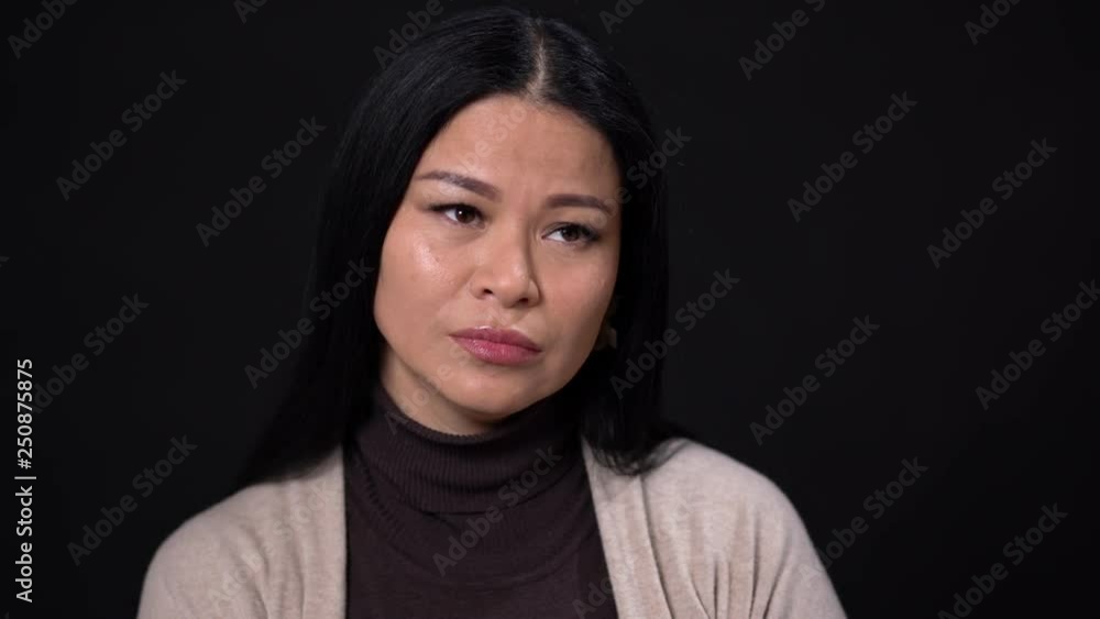 Beautiful Brunette Model with Narrow Eyes on a Black Background.