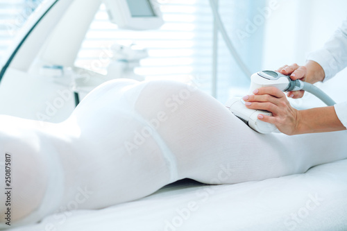 Tableau sur toile Buttock s area of female patient in white suit undergoing procedure beauty LPG massage, close up
