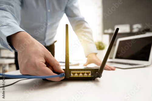 Obraz na płótnie Man connects the cable to the router's socket