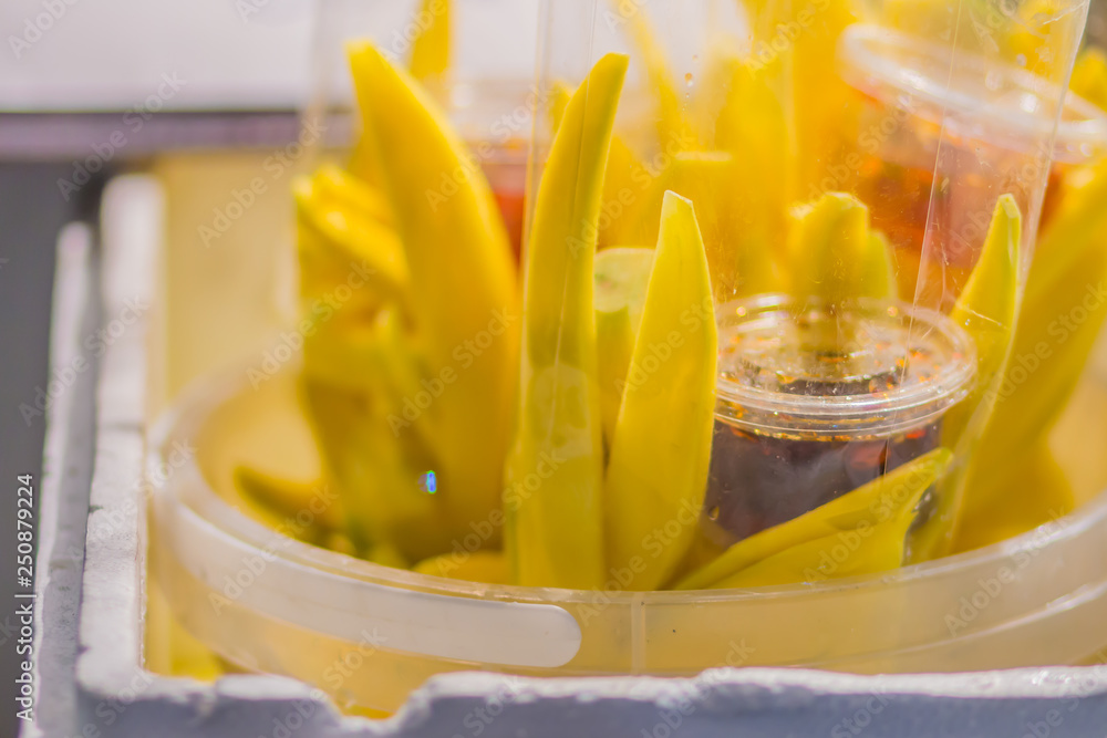 Yellow sliced mango in plastic bag with sweet sauce for sale at the fruit night market. Ready to eat sliced mango with sweet sauce in plastic bag for bring back home. Photos