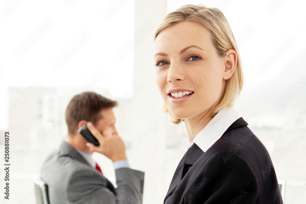 corporate businesswoman looking at camera - businessman on the phone in background - business negotiation corporate businesswoman looking at camera - businessman on the phone in background - business negotiation