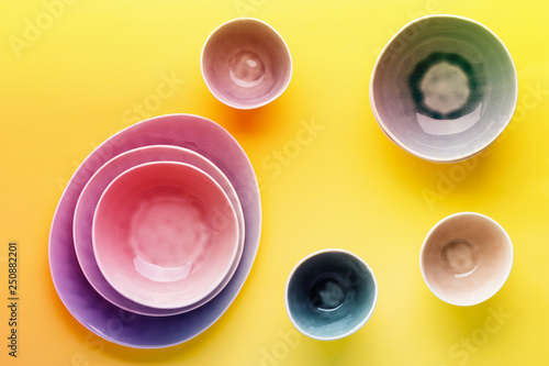 Beautiful blue, grey, beige dinnerware, plates bowls on yellow background table, top view, vibrant toned, neon colors, selective focus