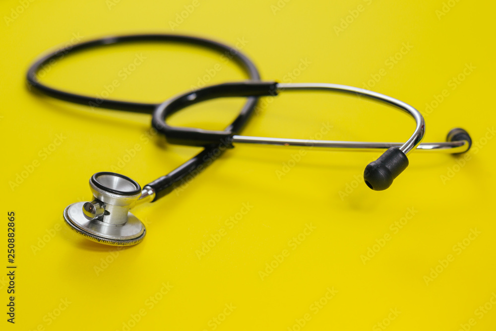 closeup view of stethoscope on yellow background closeup view of stethoscope on yellow background