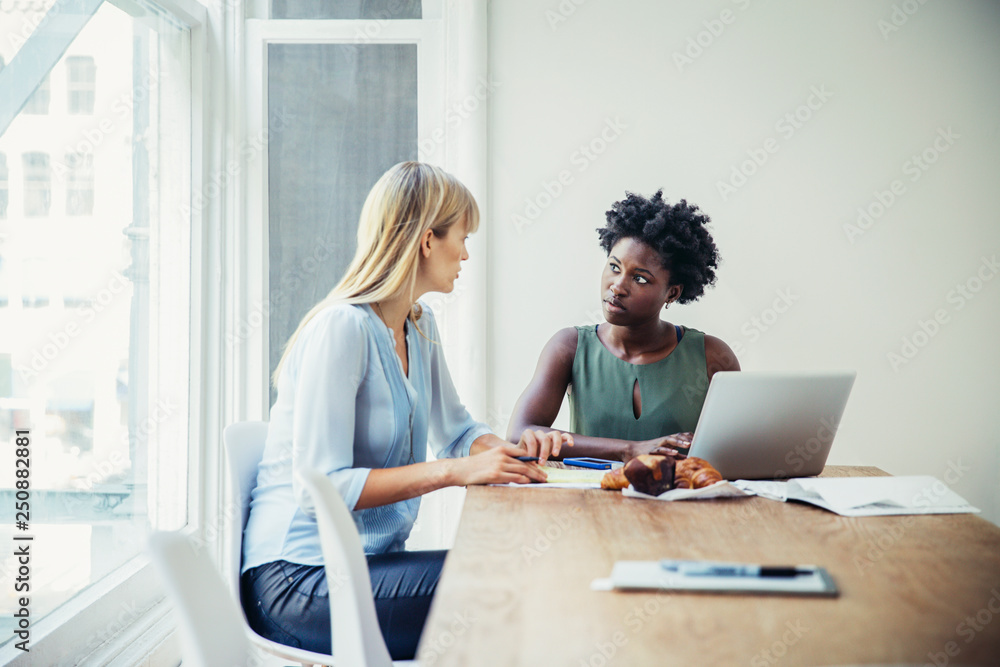 Two businesswomen talking at desk Two businesswomen talking at desk