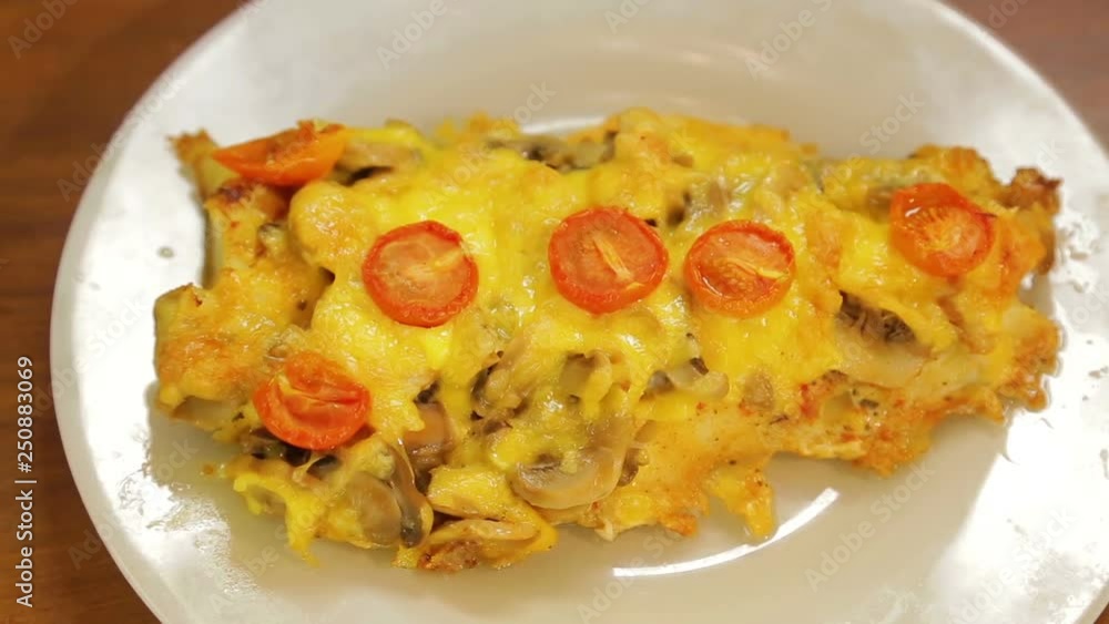 Baked fish in cheese with mushrooms and cherry tomatoes on a white plate Baked fish in cheese with mushrooms and cherry tomatoes on a white plate