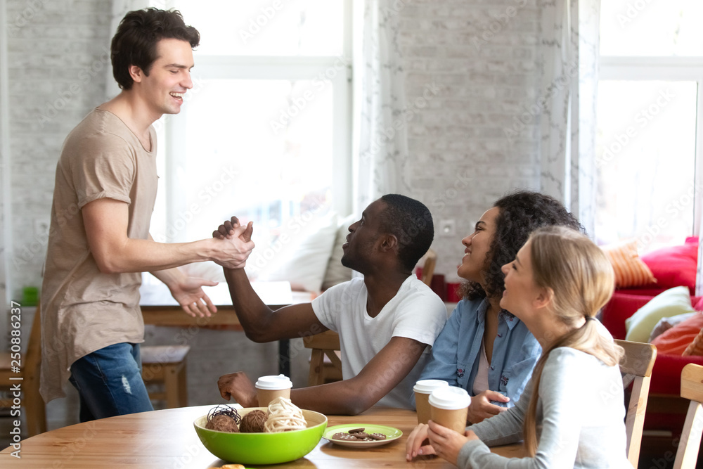 Smiling Caucasian man shaking hand of African American friend