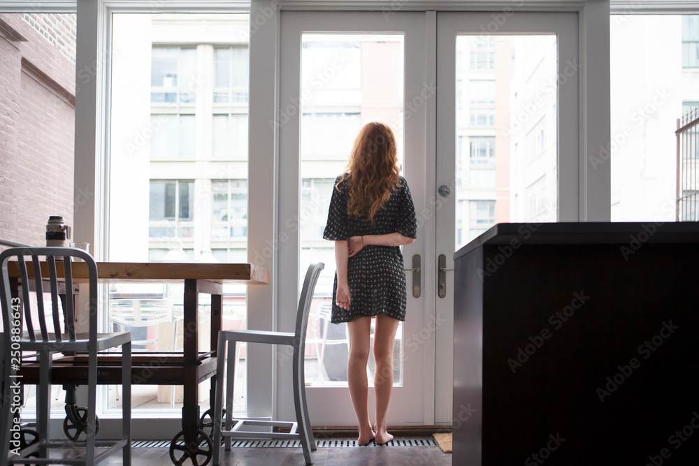 Young woman looking through window Young woman looking through window
