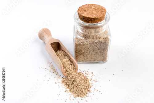 ground white pepper in wooden scoop and jar on isolated on white background