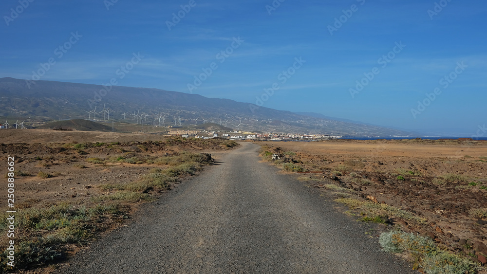 Empty road cutting through the arid volcanic lanscape of Tenerife island, road from Faro Punta de Abona towards the village Poris de Abona, concept for going the extra mile or clear work and lifestyle