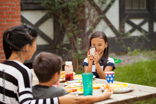 Girl (8-9) taking picture of her mother and brother (6-7) with smartphone  photo