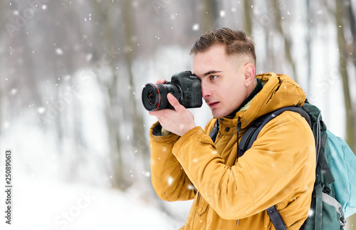 Photograph boy shooting winter landscapes while walking in the forest © proimagecontent