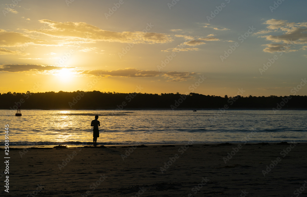 Distant silhouette of fisherman casting into Tauranga Harbour entrance,