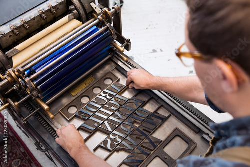 Man adjusting printing blocks on traditional letterpress in workshop  photo