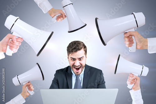 Photography Stressed man with laptop, hands with megaphones