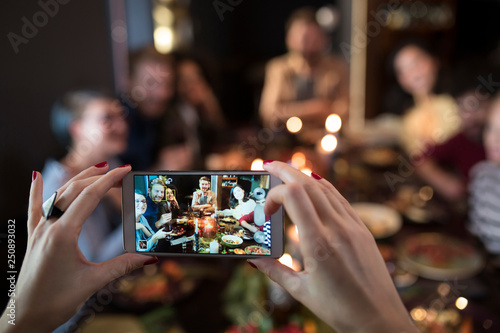 Woman's hands taking photo of friends dining  photo