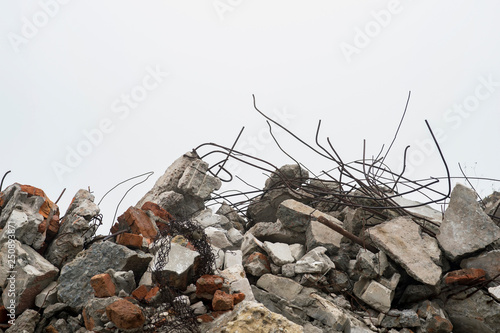 The rebar sticking up from piles of brick rubble, stone and concrete rubble against the sky in a haze.