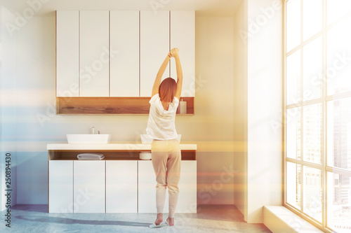 Woman in white and wooden bathroom, double sink © ImageFlow