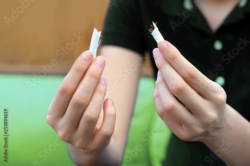 Hands young woman tearing a cigarette. Girl holding a broken cigarette in her hands. The concept of a healthy lifestyle. Quit smoking.